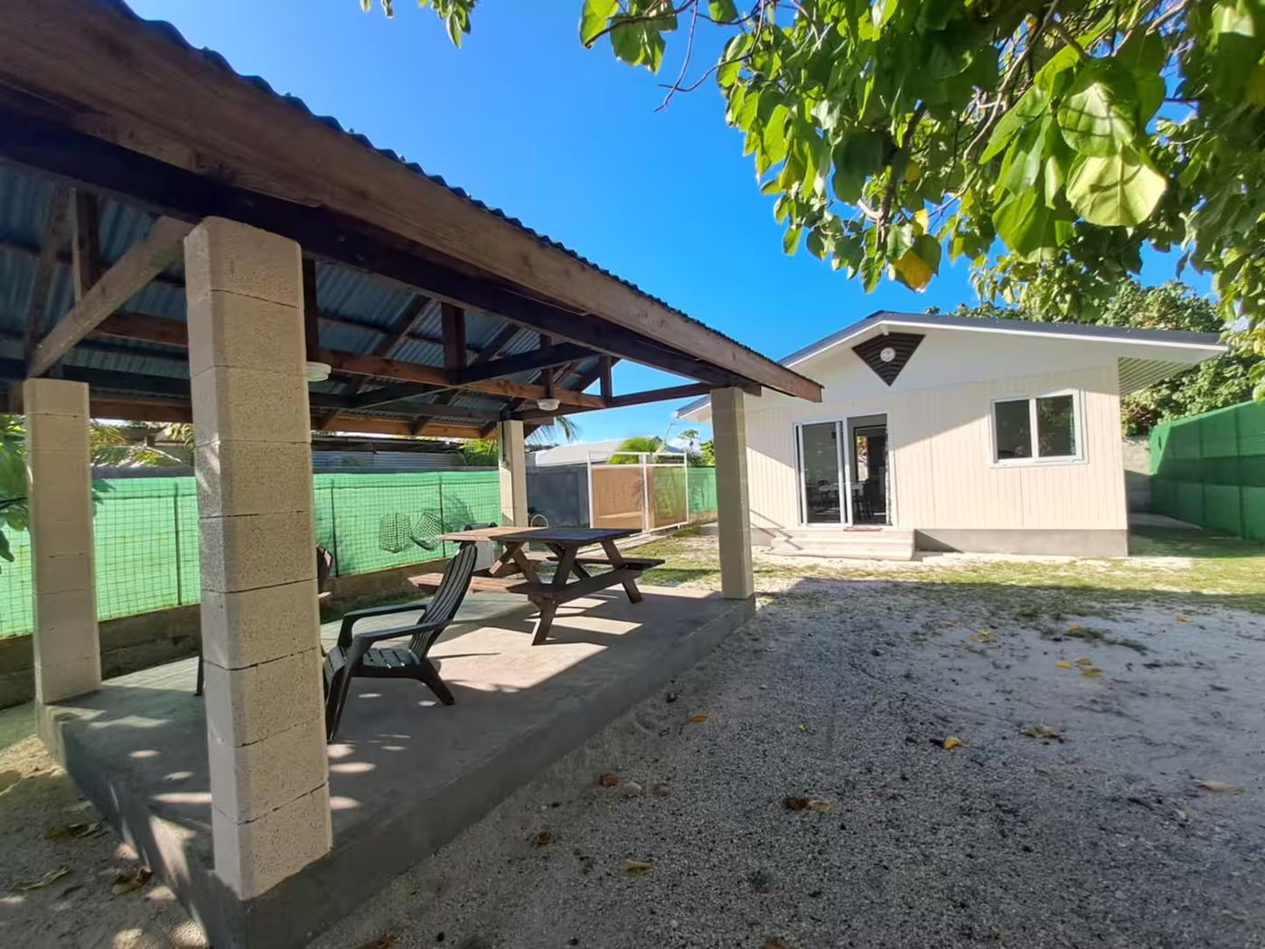 Le Fare Kahaia, petit bungalow au toit rouge et à la terrasse blanche, entouré de cocotiers.