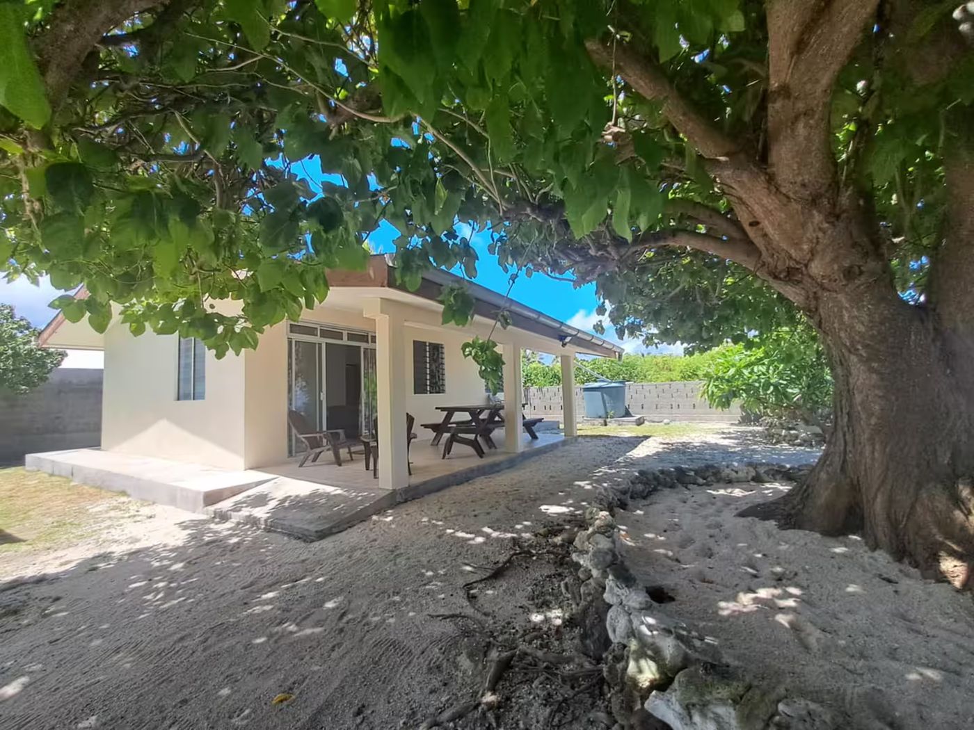 Le Fare Tipanier et sa terrasse couverte, à l'ombre d'un grand arbre du village.